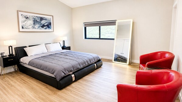 Een slaapkamer met een bed, nachtkastjes, een rode stoel, een kledingkast en een raam.