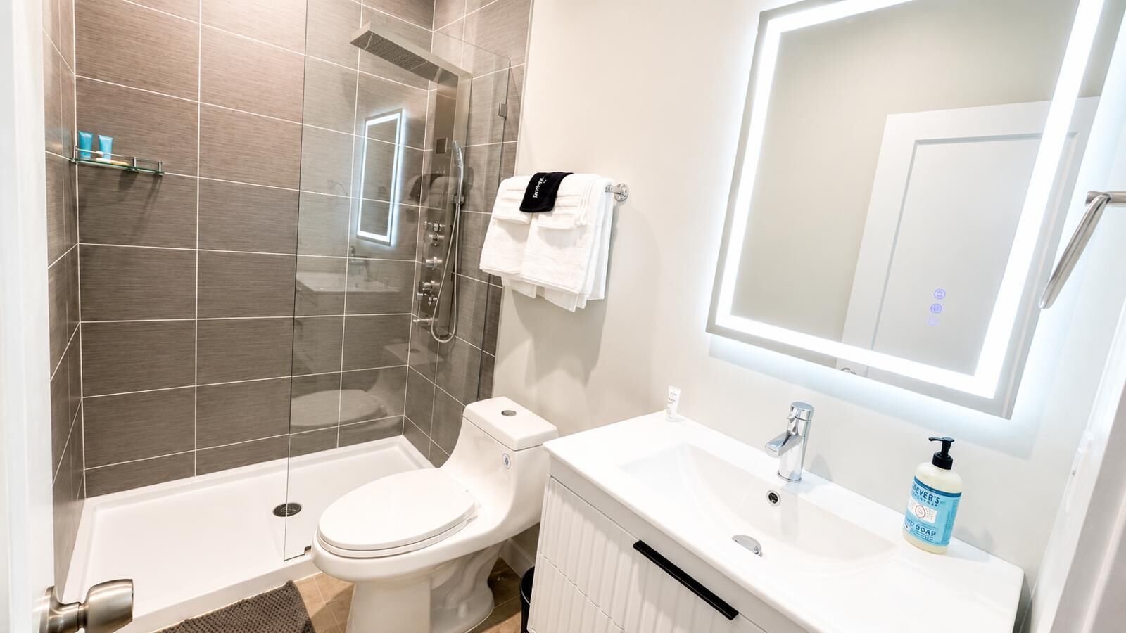 A modern bathroom with a shower, toilet, and sink.