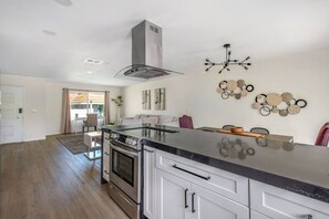 A modern kitchen with a central island, stainless steel appliances, and a pendant light.