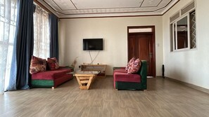 A living room with two sofas, a coffee table, and a television on the wall. - Ridgeway Victoria (Entebbe)