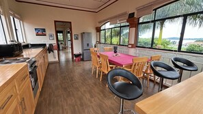 Een ruime keuken met houten kasten, een eettafel met stoelen en een uitzicht door grote ramen.