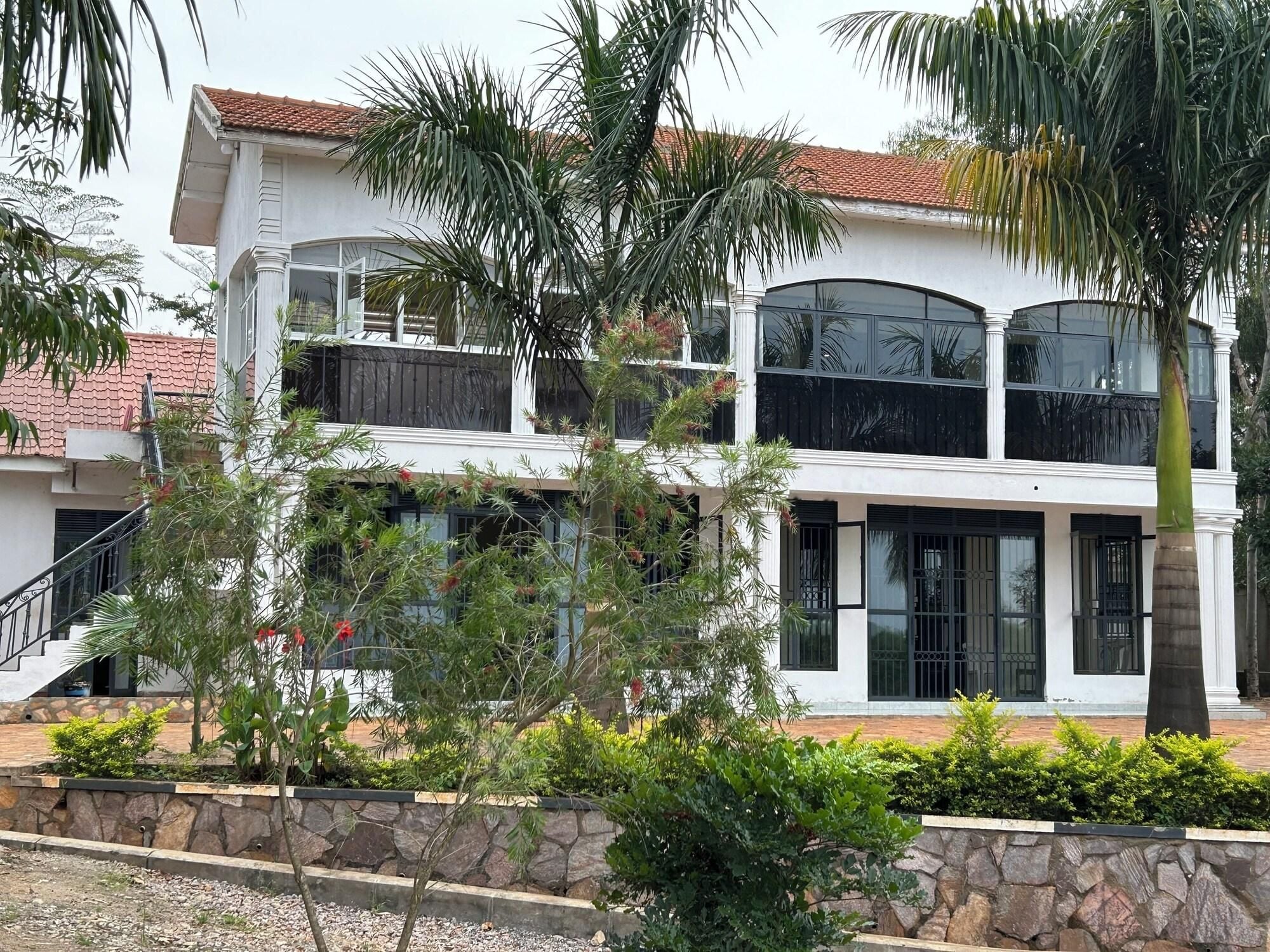 A two-story building with a white facade, large windows, and a stone retaining wall.