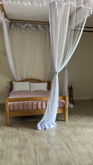 A bed with a canopy, wooden headboard, and a light-colored mattress. - Ridgeway Victoria (Entebbe)