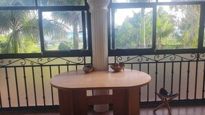 A wooden table with two bowls on it, positioned in front of a window with a view of greenery. - Ridgeway Victoria (Entebbe)