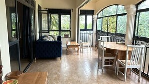 Ein geräumiges Zimmer mit großem Esstisch, einer Couch und Blick durch große Fenster.
