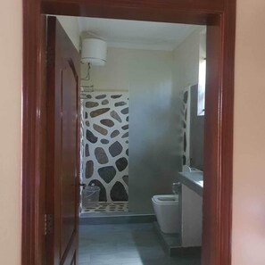 A bathroom with a toilet, sink, and a mirror. - Ridgeway Victoria (Entebbe)