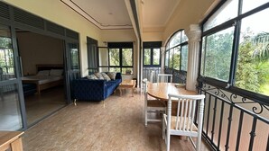 Ein Balkon mit Esstisch und Stühlen, ein Sofa und ein Bett im angrenzenden Zimmer.