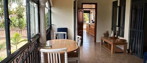 Un pasillo con comedor que incluye una mesa y sillas, vistas amplias a través de grandes ventanales y una zona de cocina al fondo.