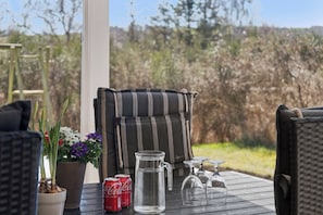 A patio with outdoor furniture, a metal pitcher, two Coca-Cola cans, a potted plant, and a wicker chair.