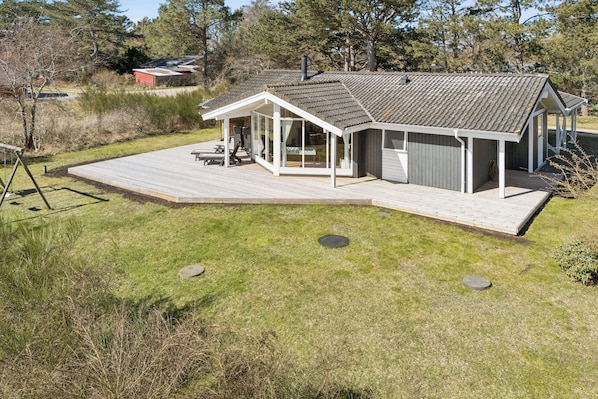 A modern house with a large deck, a covered patio, and a garage.