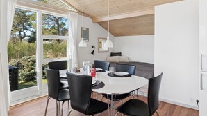 A dining area with a round table, black chairs, and a view of the outdoors.