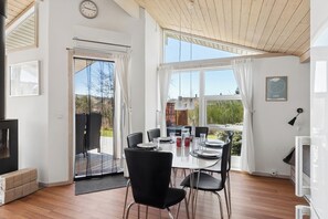 A modern room with a dining table, chairs, a TV, and a large window with curtains.