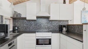 Cozinha moderna com armários brancos, bancada preta e painel de azulejos.