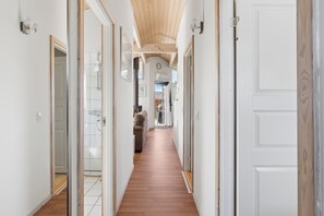 A hallway with wooden flooring, white walls, and doors leading to different rooms. - Spa holiday home by Høve Beach (Asnæs)