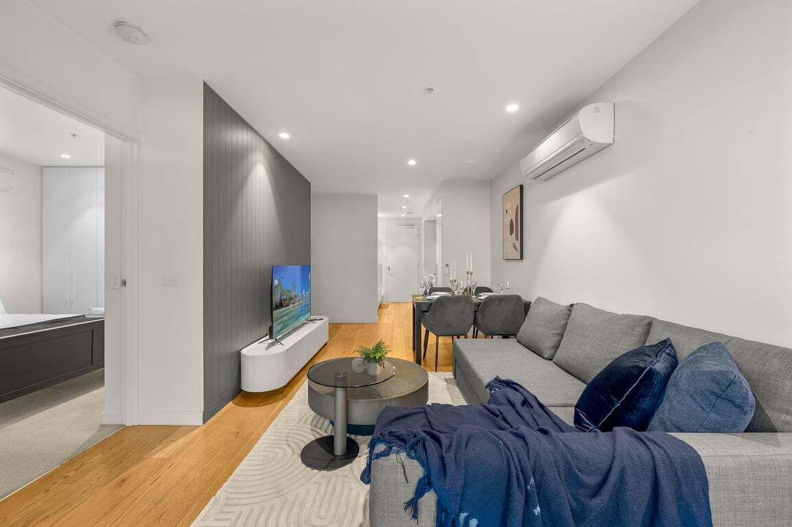 A modern living room with a grey sofa, a coffee table, and a TV.