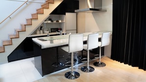 Eine moderne Küche mit Kochinsel, Barhocker, Mikrowelle und einer Treppe.