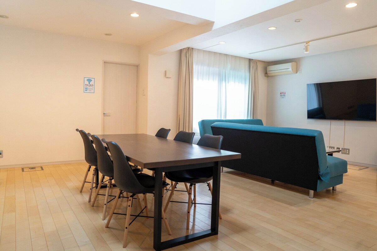 Ein modernes Zimmer mit Esstisch, Stühlen, einer Couch, einem Fernseher und einer Klimaanlage.