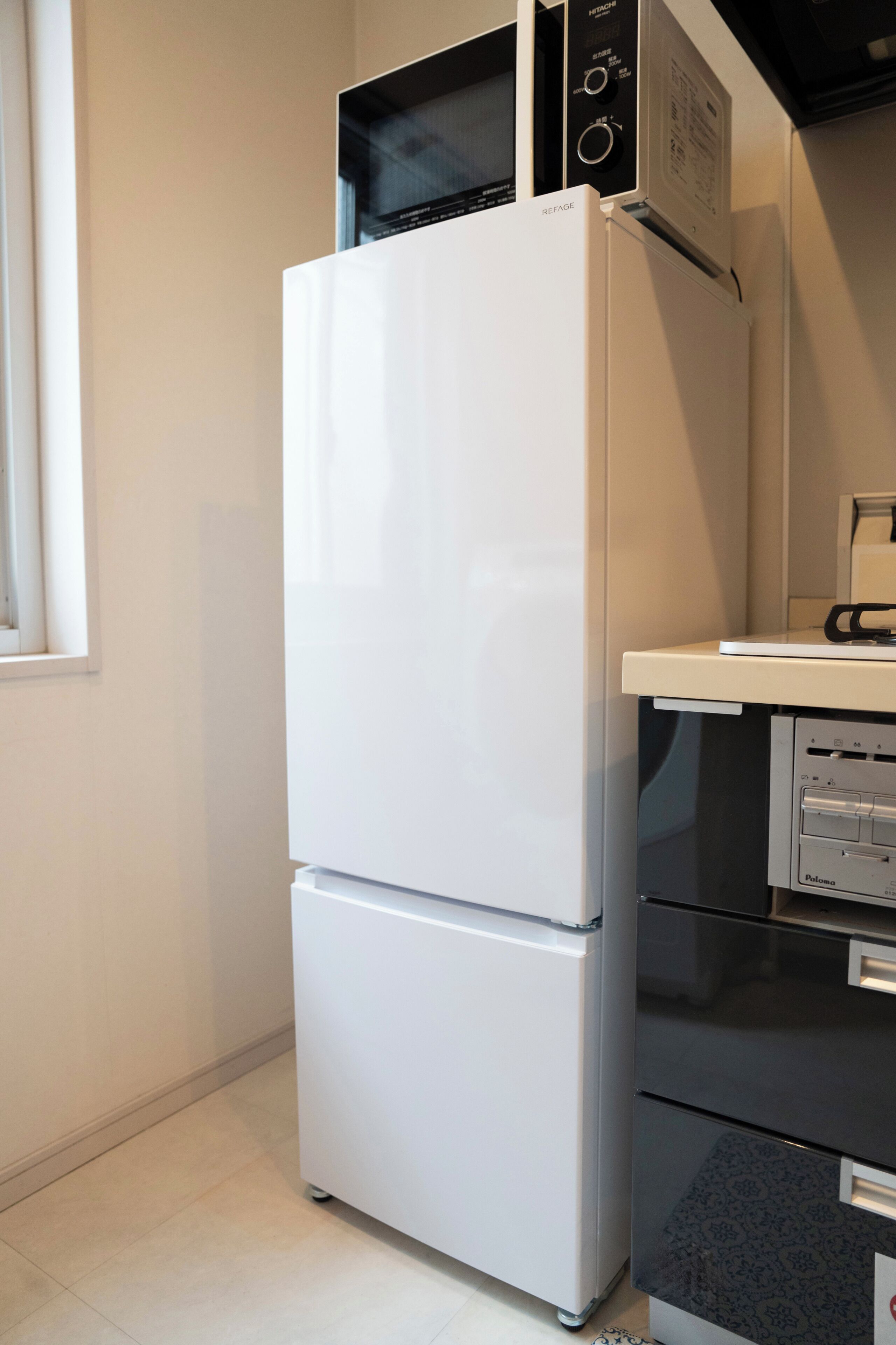 Een keuken met een witte koelkast, een magnetron en een koffiezetapparaat op het aanrecht.