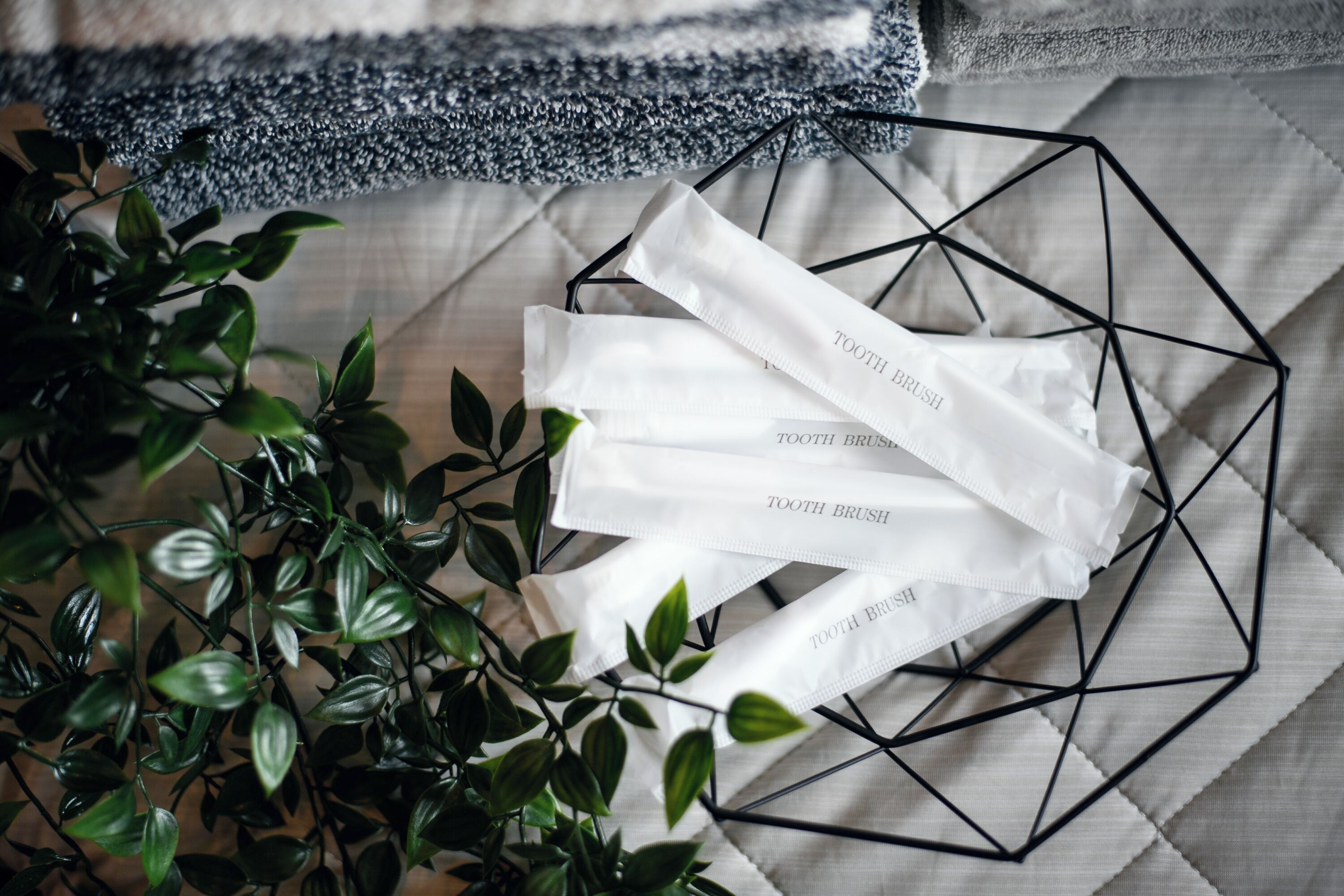 A geometric metal tray with white tissue boxes labeled 'TOOTH BRUSH' on a textured fabric surface.