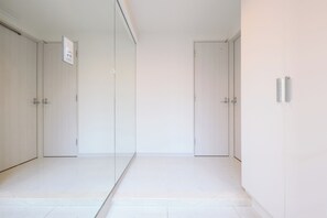 A room with a mirrored closet, a door with a handle, and a light switch on the wall. - SHIBUYA CITY HOUSE (Tokyo)