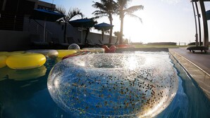 Una piscina con flotadores y palmeras al fondo.