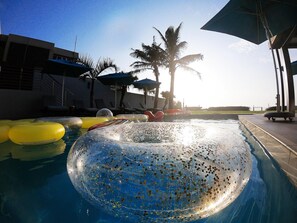 A swimming pool with inflatable rings and palm trees in the background. - Northstar Hotel (uMhlanga)