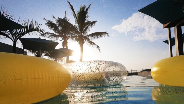 Una piscina con agua cristalina, palmeras y un cielo despejado.
