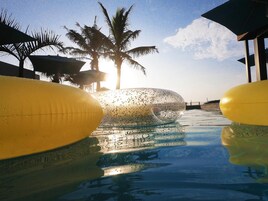Una piscina con agua cristalina, palmeras y un cielo despejado.