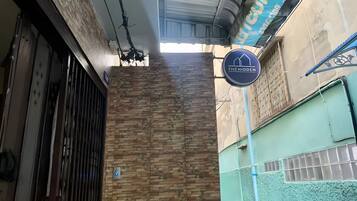 A building facade with a brick wall, a metal gate, and a sign for 'The Hidden'.