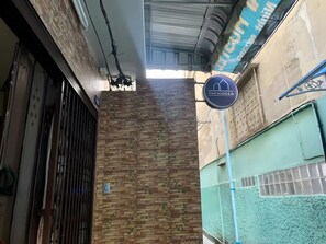 A building facade with a brick wall, a metal gate, and a sign for 'The Hidden'. - The Hidden Giant Swing (Bangkok)