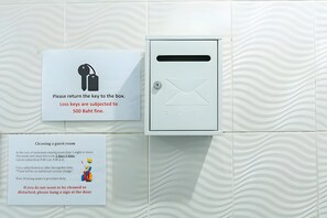 A hotel room with a key box and a sign detailing cleaning policies. - The Hidden Giant Swing (Bangkok)