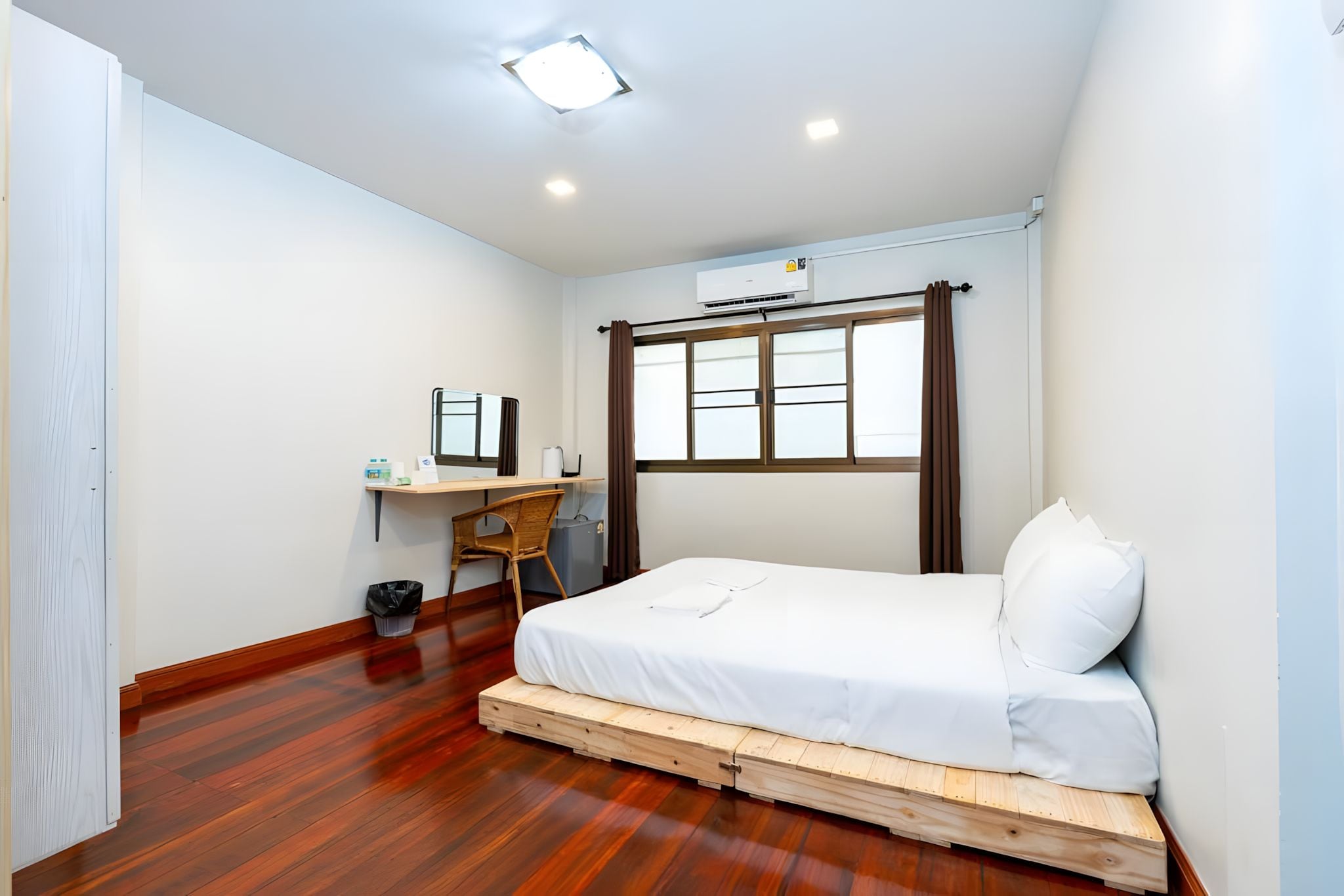 A compact bedroom with a bed, a desk, and a window.