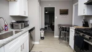 Una cocina con armarios blancos, un lavamanos de acero inoxidable, un tostador y una estufa.