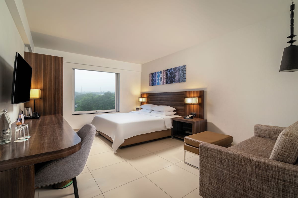 Una habitación de hotel moderna con cama, mesitas de noche, escritorio, silla y televisor.
