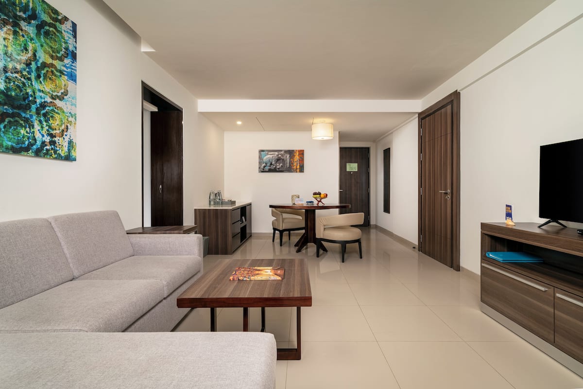 Una sala moderna con sofá, mesa de centro, mesa de comedor, sillas y televisor.