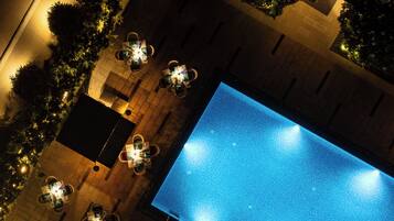An aerial view of a rooftop pool area with multiple seating arrangements and a large pool.