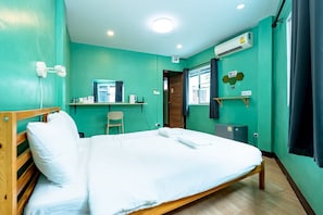 Habitación de hotel con cama, escritorio, silla, equipo de aire acondicionado y ventana con cortinas.