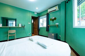 A room with a bed, a chair, a window, an air conditioning unit, and a door. - GO INN The Giant Swing (Bangkok)