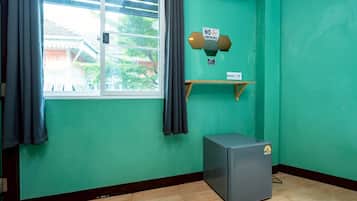 Ein Zimmer mit Fenster, einer Wand-Klimaanlage, einem kleinen Kühlschrank und einem 'RAUCHVERBOT'-Schild.