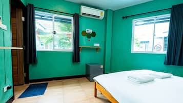 A room with a bed, a window, an air conditioning unit, a small heater, and a door.