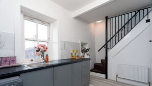 Una cocina moderna con armarios grises, encimera negra y una ventana con flores rosadas.