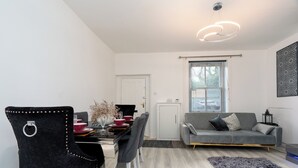 Una sala de estar moderna con un sofá gris, una mesa de comedor con sillas y un tapete decorativo.