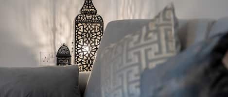 Una cama con almohadones estampados y un aplique decorativo en la pared.