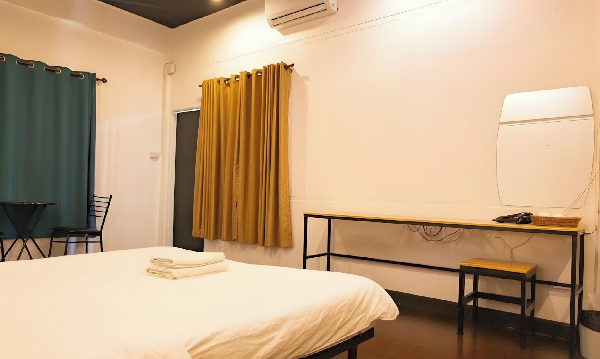 Una camera d'albergo con un letto, una scrivania, una sedia e una finestra con tende.