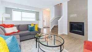 Ein modernes Wohnzimmer mit einer Couch, einem Glastisch, einem Kamin und einer Treppe.