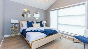 Ein modernes Schlafzimmer mit einem großen Bett, Nachttischen und einem großen Fenster.