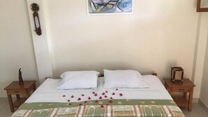 A bedroom with a bed, two nightstands, a wall clock, a framed abstract painting, and a decorative item on the nightstand. - La Casa de Jessy (Máncora)
