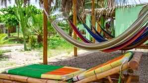 A hammock between bamboo poles, a green mat, and a wooden bench. - La Casa de Jessy (Máncora)