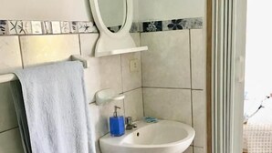 A bathroom with a white sink, a towel hanging on the wall, and a mirror. - La Casa de Jessy (Máncora)