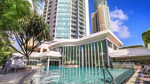 Un hotel con piscina, arquitectura moderna y edificios altos al fondo.